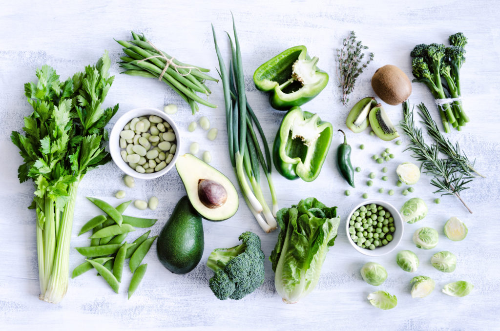 Green vegetables, fruit and spices on a grey background