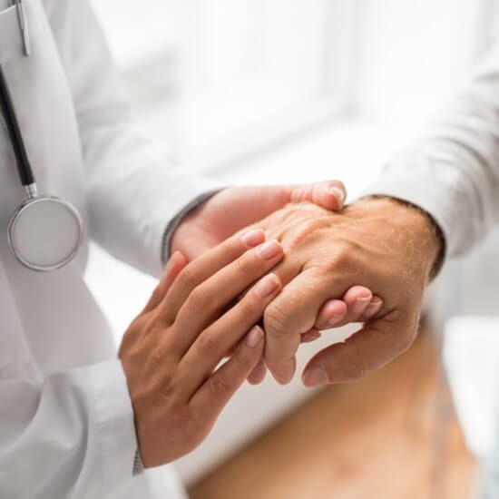 A doctor is compassionately holding the hand of an elderly patient.