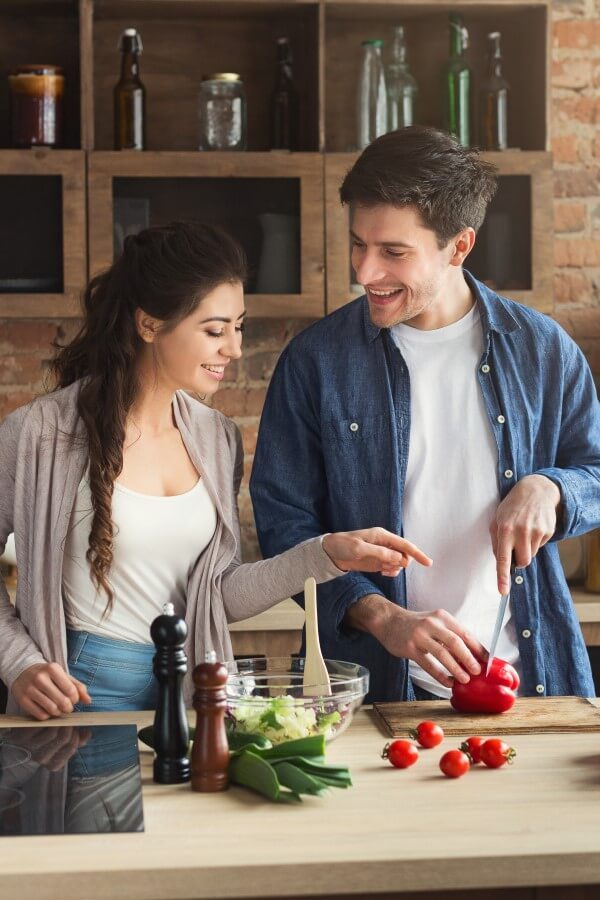 A happy young couple is cooking together in their kitchen.