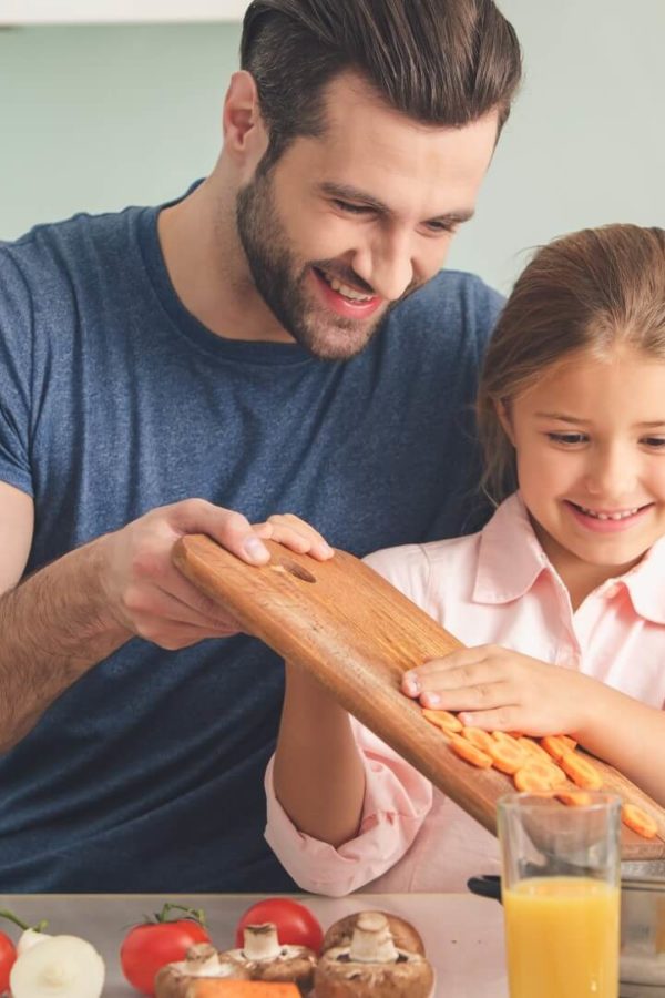 A young father and his daughter are preparing lunch together.