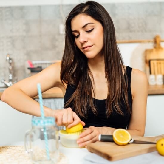 Eine junge Frau presst Zitronensaft aus, um Limonade zu machen, denn Zitronen enthalten viel Vitamin C.