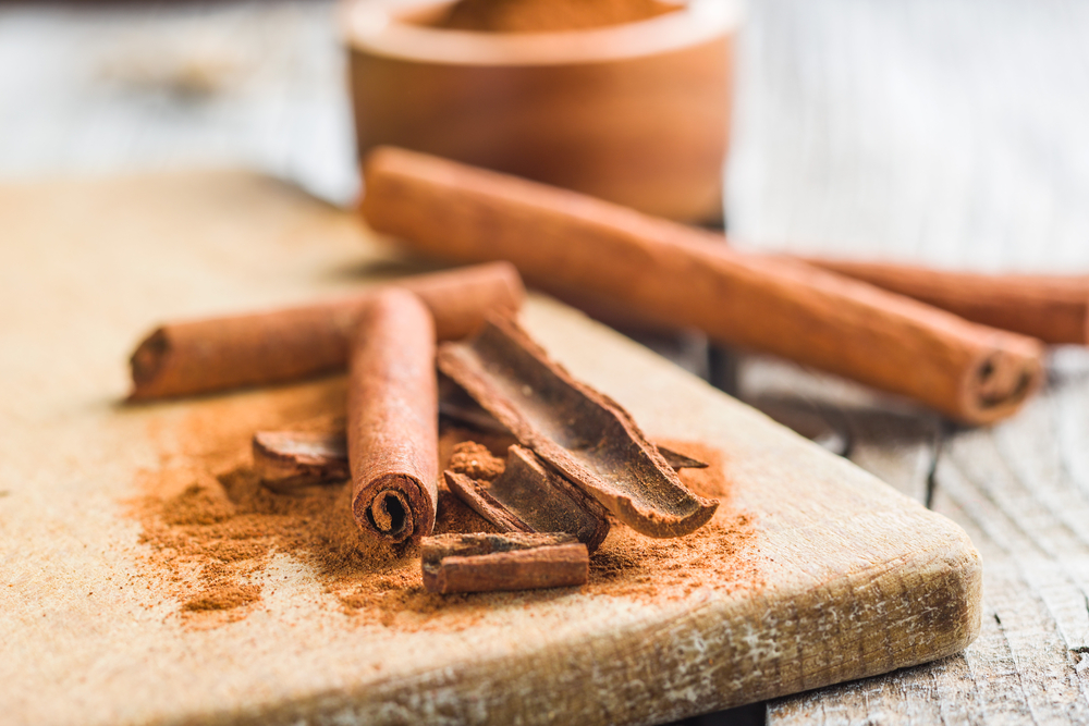 Cinnamon sticks and ground cinnamon on an old wooden board.