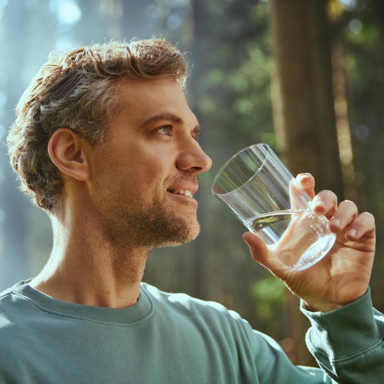 L'uomo beve acqua da un bicchiere.