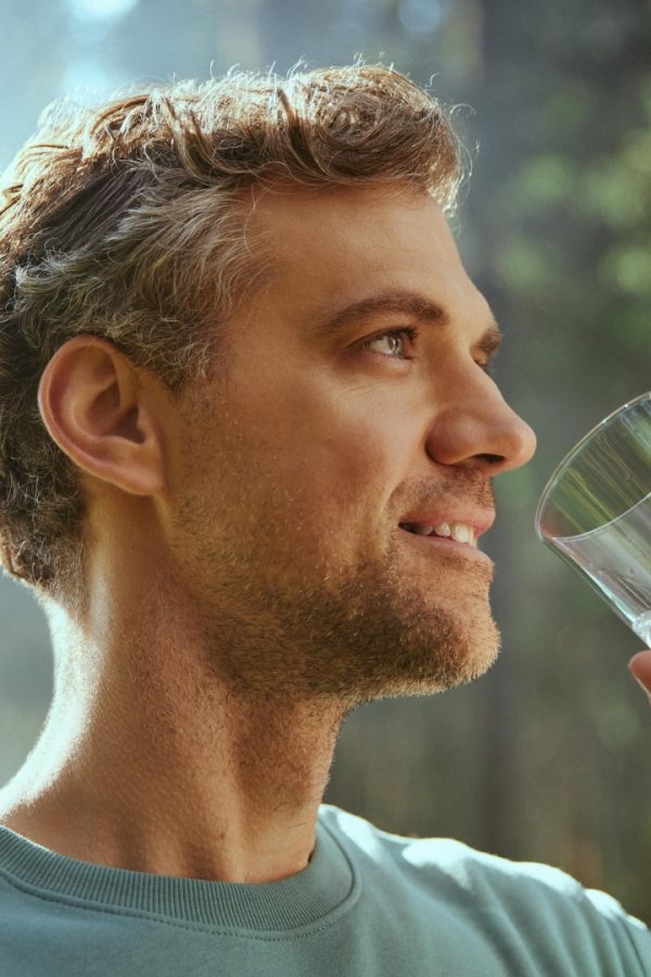 The man drinks water from a glass.