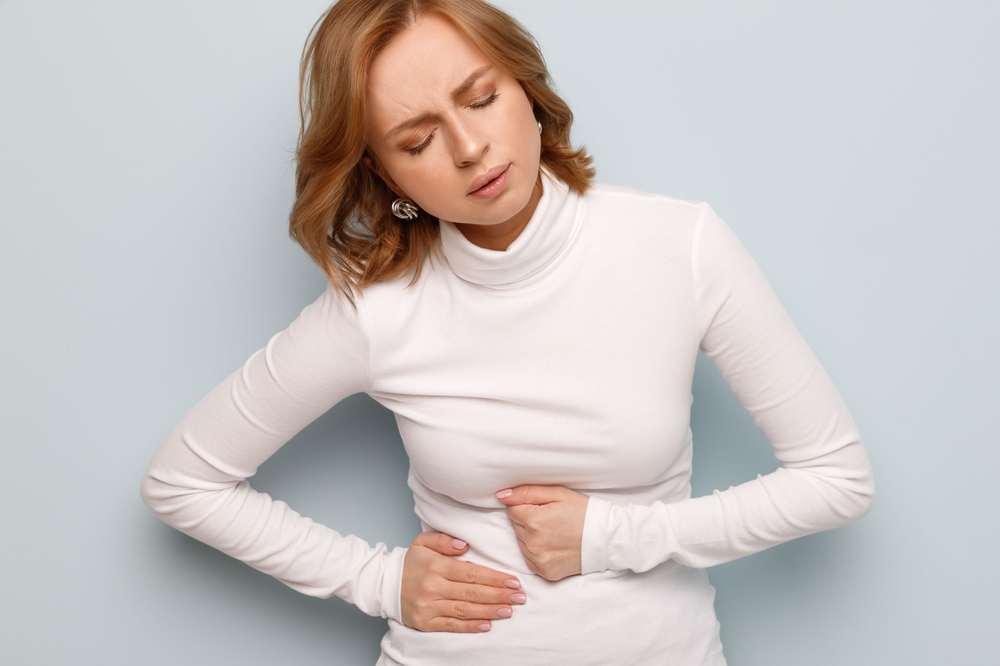 A woman holds on to her belly because she is bloated.