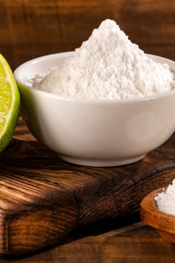 Baking soda on a wooden spoon and in a ceramic cup.