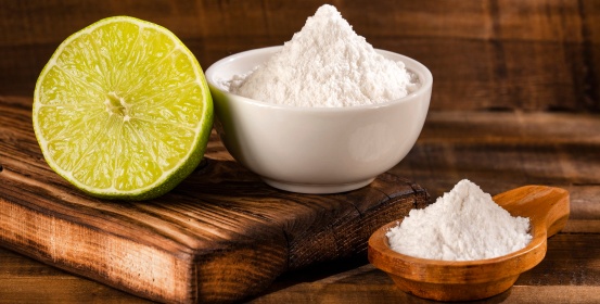 Baking soda on a wooden spoon and in a ceramic cup.