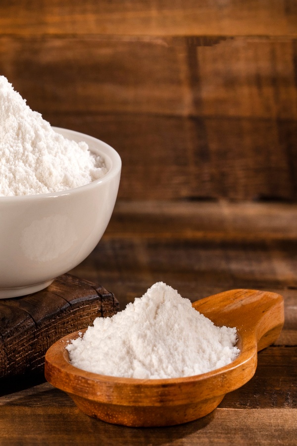 Baking soda on a wooden spoon and in a ceramic cup.