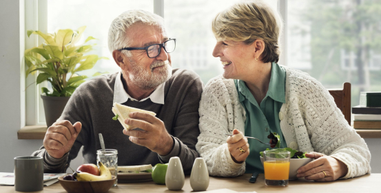 An elderly couple at the table has a healthy and tasty dinner.